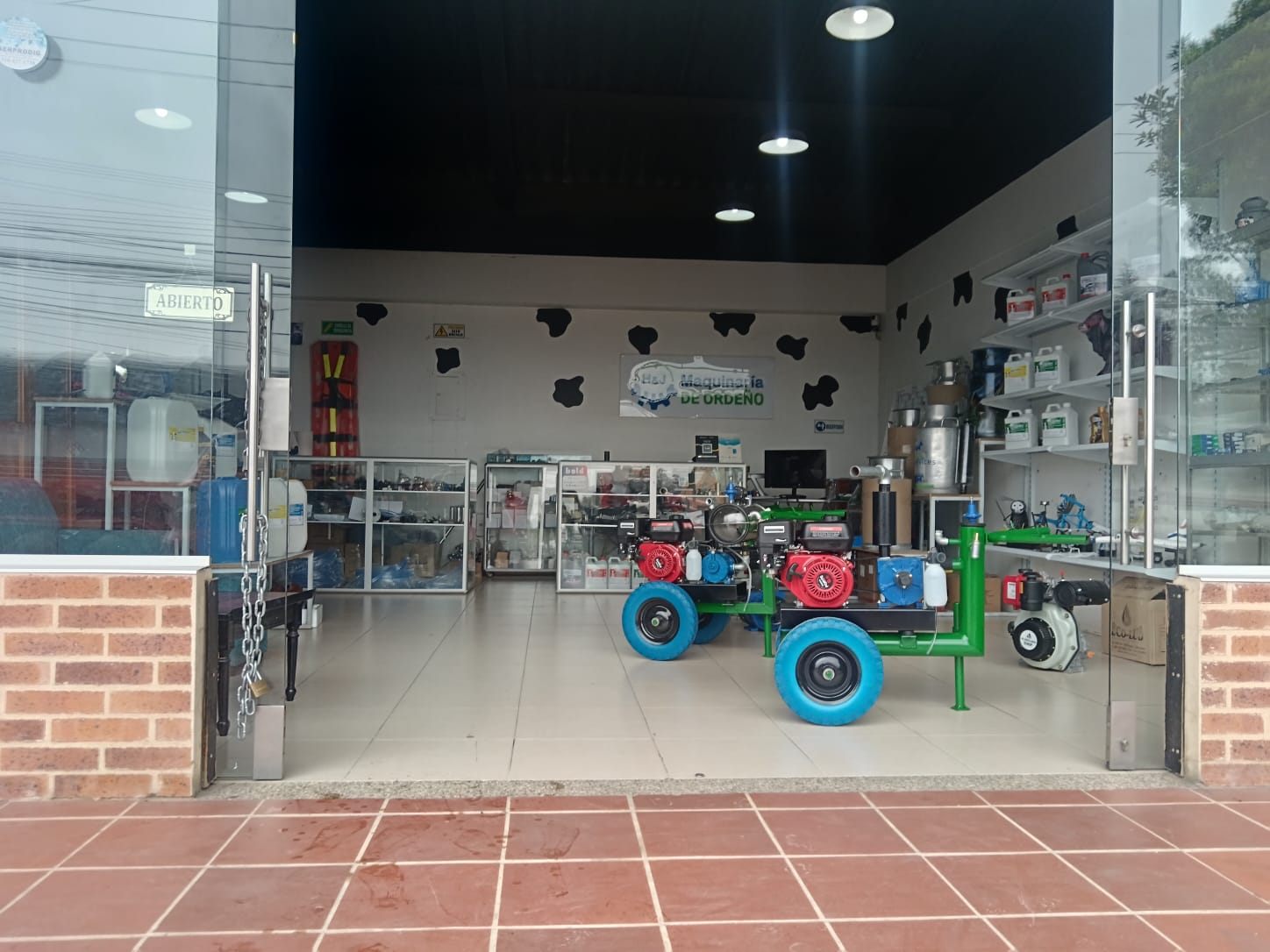 Entrada del local de H&J en Zipaquirá con el aviso de abierto y máquinas de ordeño a la vista