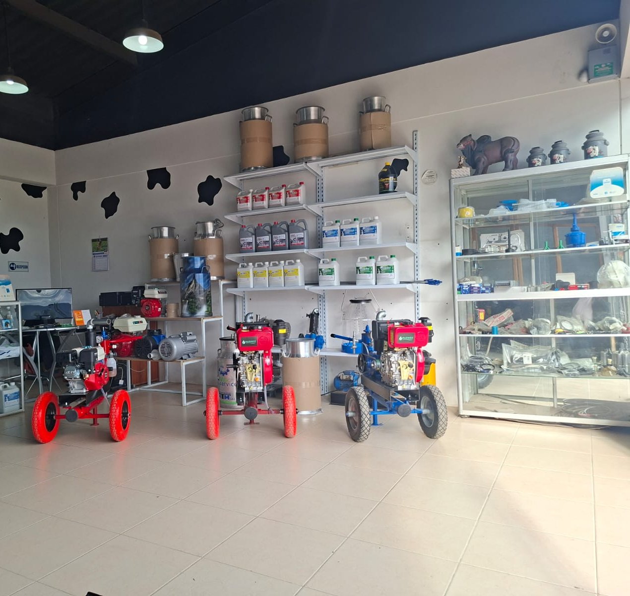 Piso de venta del local H&J en Zipaquirá: máquinas de ordeño portátiles, estantes con detergentes y selladores, cantinas y vitrinas de repuestos
